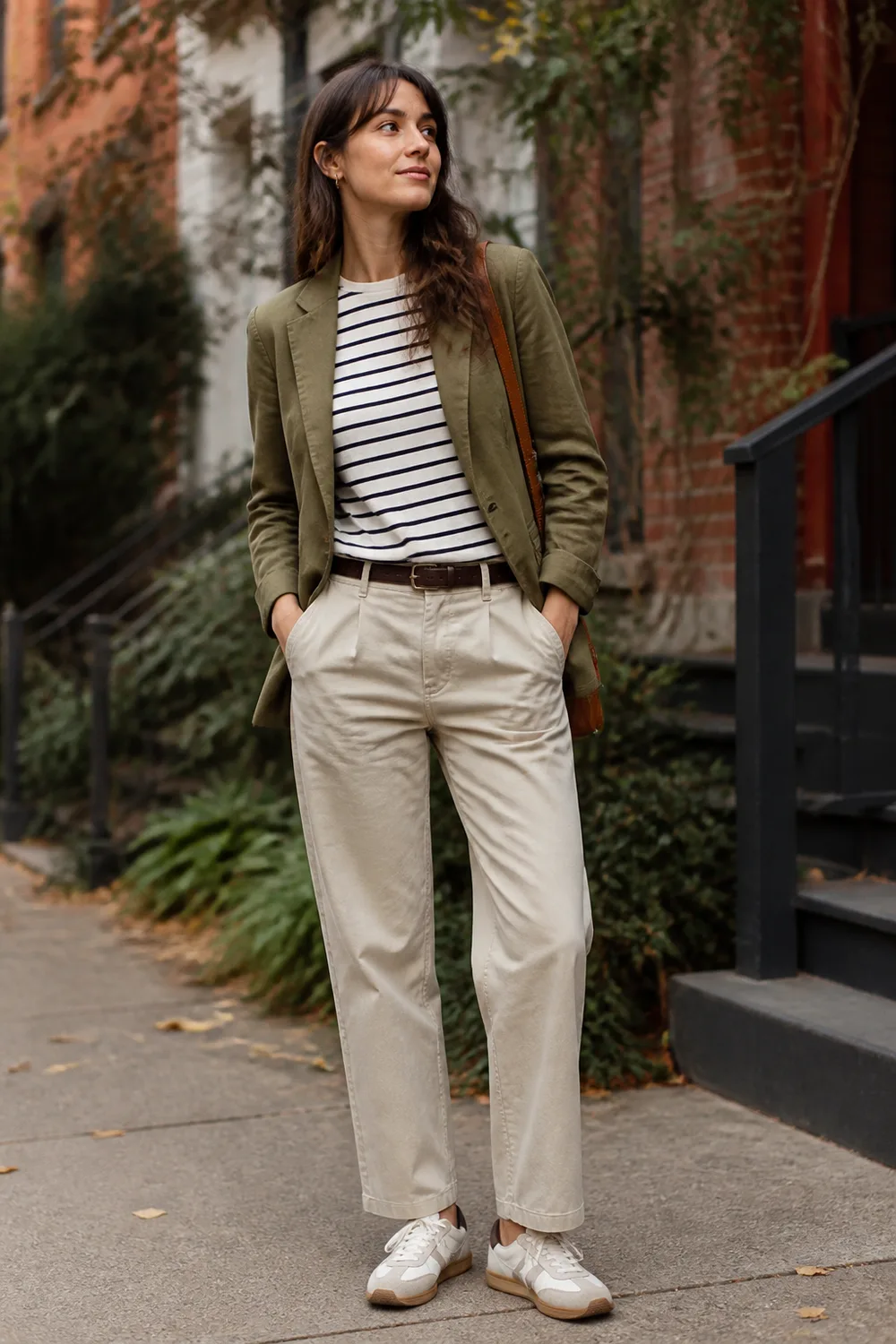 Woman wearing an olive blazer, striped T-shirt, stone chinos, and retro sneakers